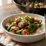 Ingredients for black pepper chicken stir fry including chicken thighs, bell peppers, onion, chilies, garlic, ginger and soy sauce